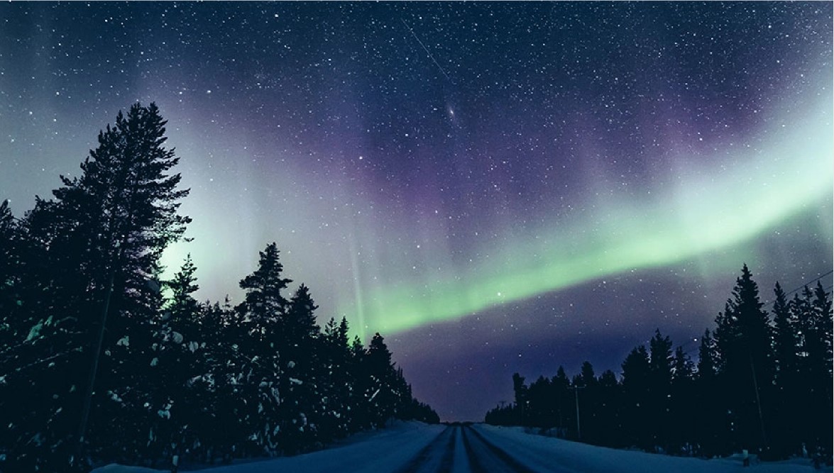 Aurores boréales en hiver sur une route enneigée